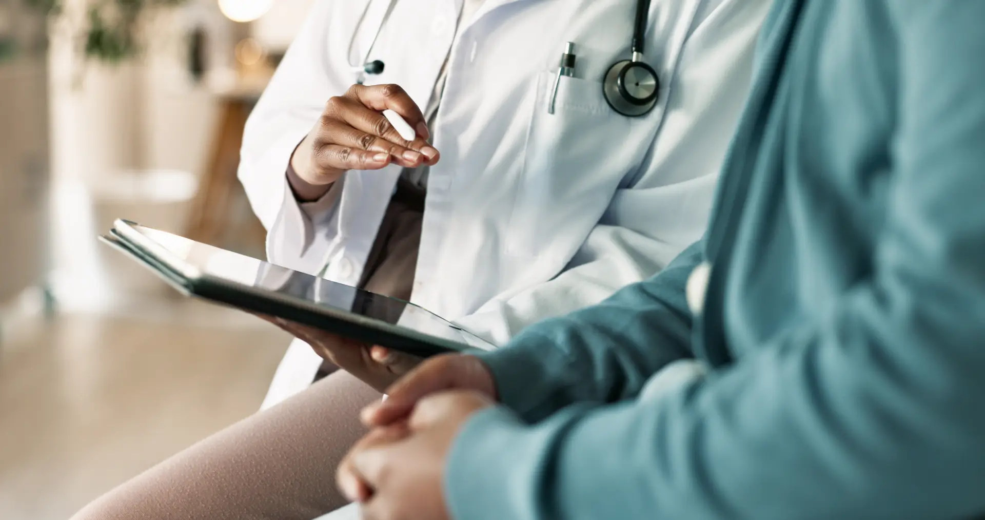 Doctor consulting patient using digital tablet.