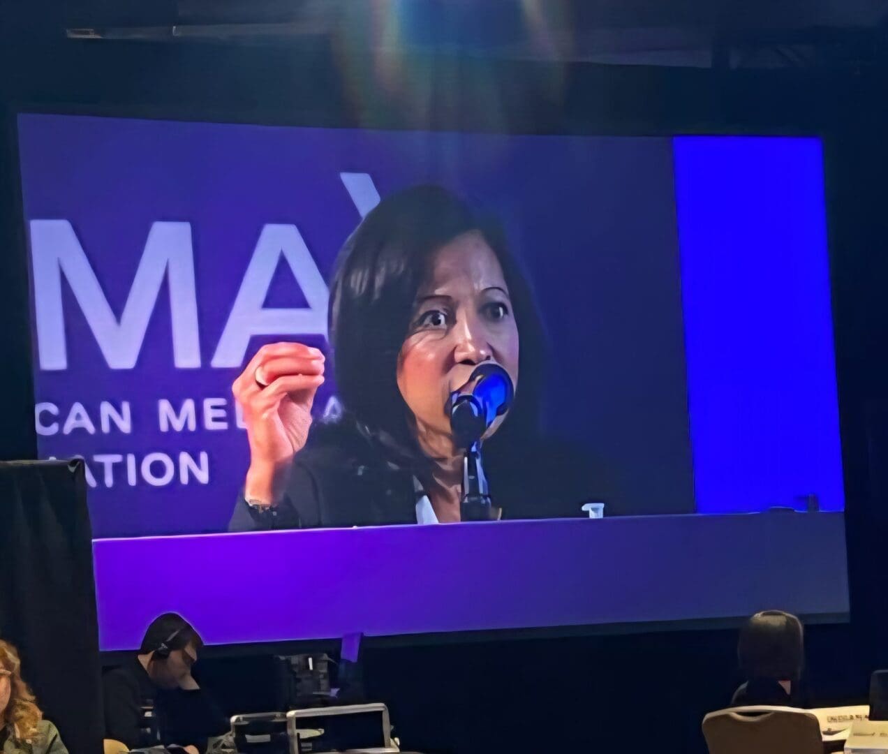 Woman speaking at a conference with a microphone.